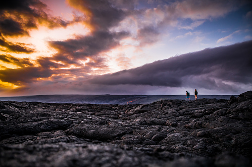 Heterosexual Couple Hiking Volcanic Landscape Epic Sunset Cloudscape Hawaii Lava Rock Clouds Vacation Travel Destination. Alien Landscape.