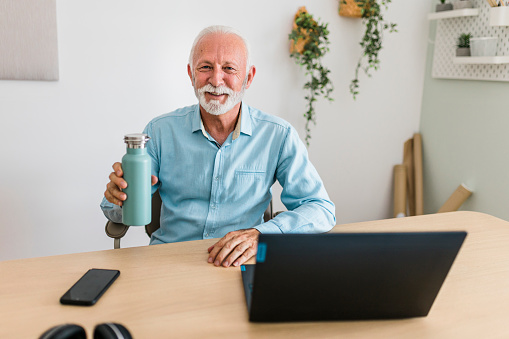 Portrait of senior businessman drinking water from reusable bottle