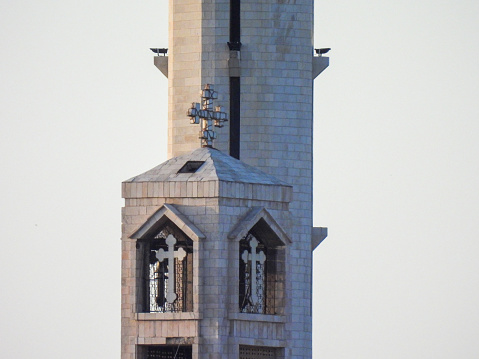 A vertical shot of a church tower with a clock and silhouetted trees against a blue evening sky