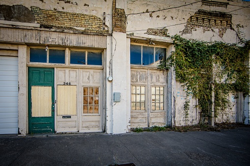 McKinney, United States – April 20, 2023: An old, dilapidated abandoned building with green foliage on the wall.