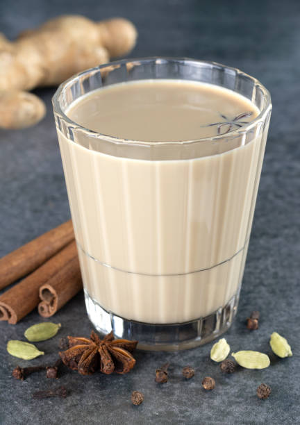 A glass of Indian masala tea with spices - cinnamon, star anise, cloves, cardamom on a gray background. A glass of Indian masala tea with spices - cinnamon, star anise, cloves, cardamom on a gray background. ayurveda cardamom star anise spice stock pictures, royalty-free photos & images