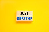 Just breathe and psychological symbol. Concept words Just breathe on beautiful wooden block. Beautiful yellow table yellow background. Business psychological and Just breathe concept. Copy space