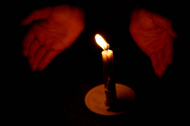 istock candle flame illuminates a female hand in a dark room 1484202502
