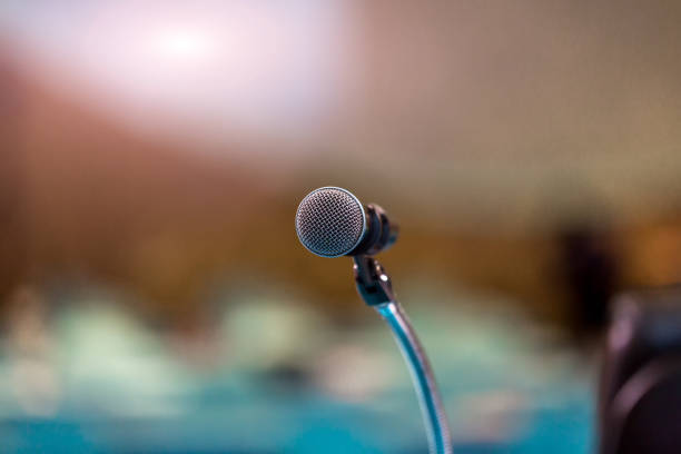 Microphone in concert hall or conference room soft and blur style for background. Microphone over the Abstract blurred photo of conference hall or seminar room background.