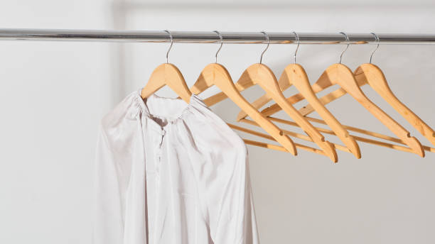 silk beige shirt hanging on a wooden hanger close-up. concept of online store. silk beige shirt hanging on a wooden hanger close-up. concept of online store. panoramic banner clothes hanger rod stock pictures, royalty-free photos & images