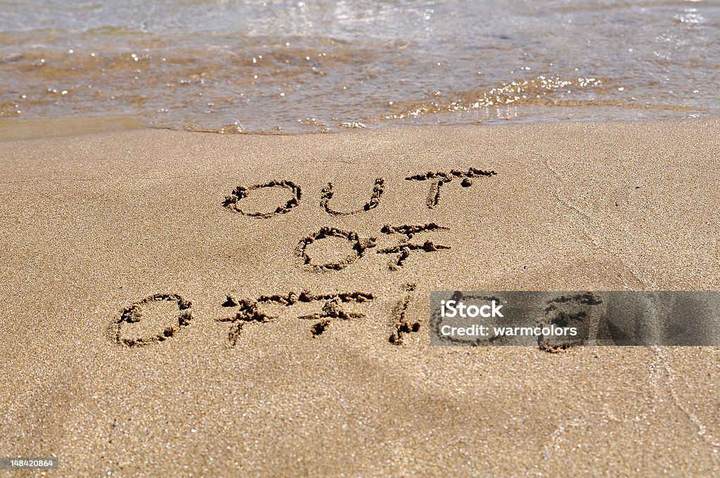 Out of office message written in the sand of a beach Out of office text written on the beach sand After Work Stock Photo