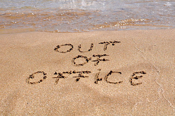 Out of office message written in the sand of a beach stock photo