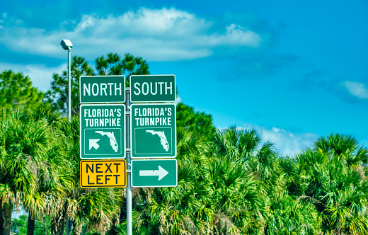 Florida's turnpike road signage against palms and blue sky.