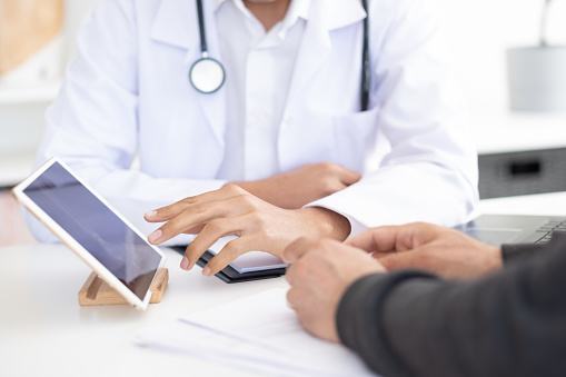 Doctor and patient examining x-ray images from digital tablet