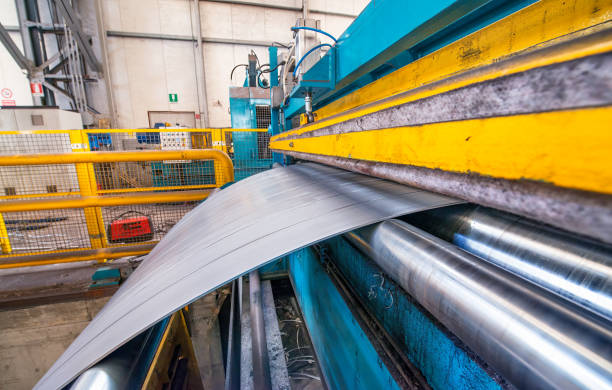 Cutting machine with roll of galvanized steel sheet. Ironworks and metalwork manufacturing factory for production of metal pipes and tubes