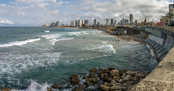 Modern city on the shore of the Mediterranean sea with high rise buildings, a sea wall, dramatic skies, Tel Aviv, Israel