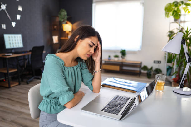 istock Young woman experiencing painful headache while working on laptop at home 1484218905
