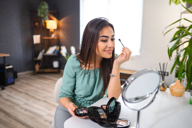 istock Beautiful young woman applying makeup at home 1484219555