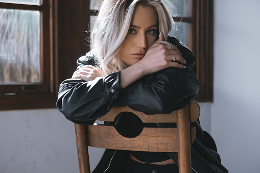 Young beautiful blonde girl sitting on a chair and looking at camera.