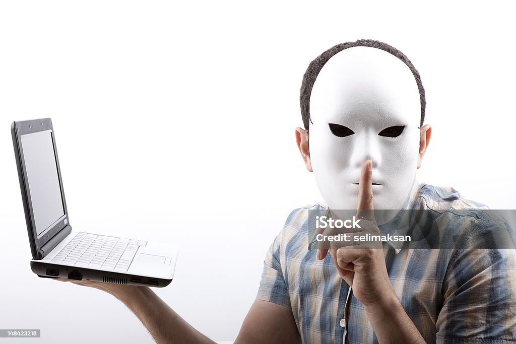 Człowiek, którego twarz zasłonięty z Maska Trzymając komputer i ostrzeżenia - Zbiór zdjęć royalty-free (Haker komputerowy)