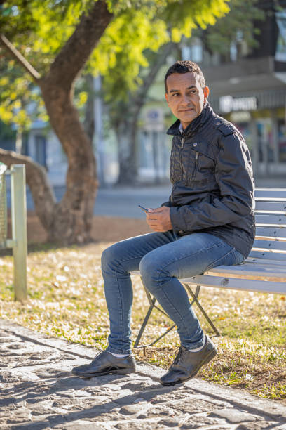 istock Young latin man sitting on a square bench. 1484233229