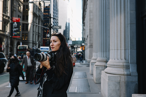 Female photographer walking and taking images on the streets of Manhattan, New York.