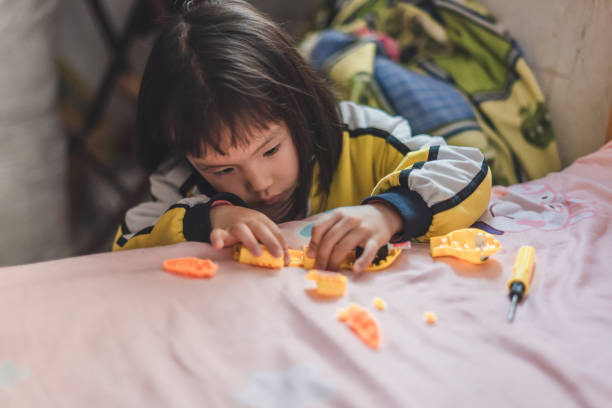 une fille asiatique répare des jouets - kit mains libres photos et images de collection