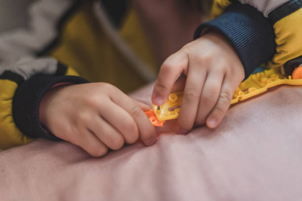 une fille asiatique installe des jouets à la maison - kit mains libres photos et images de collection