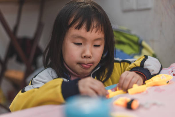 une fille asiatique installe des jouets à la maison - kit mains libres photos et images de collection