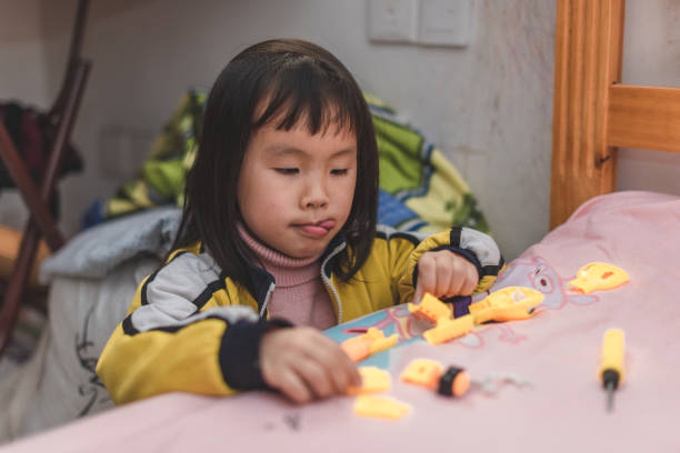 une fille asiatique installe des jouets à la maison - kit mains libres photos et images de collection