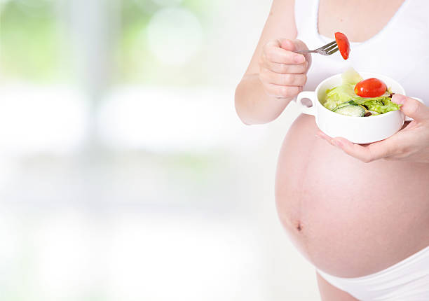 istock pregnant woman hand holding salad 148424253