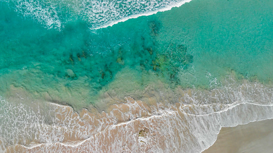 Above the ocean, aerial view at the waves and surface near shoreline - Drone viewpoint.