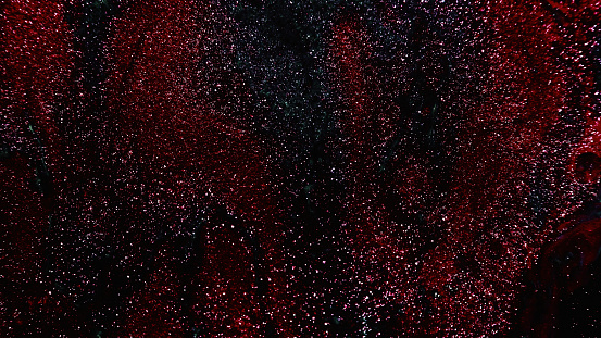 Glitter texture. Abstract background. Fantasy night sky. Defocused shiny metallic red black color grain paint sparkles on dark free space.