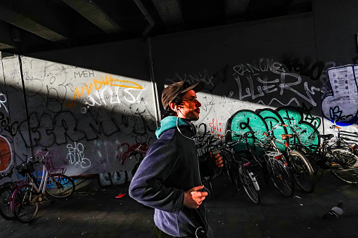 Copenhagen, Denmark April 6, 2023 A person walks through a beam of light against a graffiti wall in the Norrebro district.