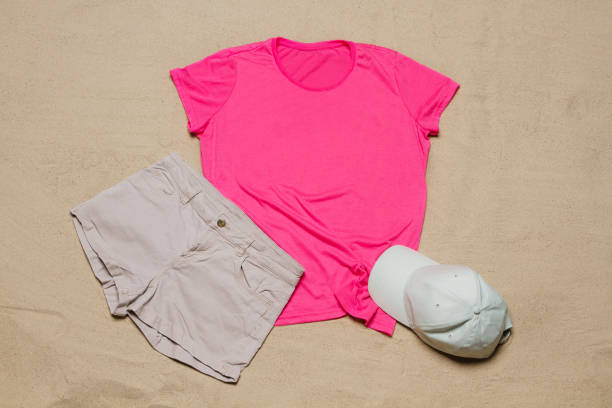 Sand beach texture background. Mockup pink summer t-shirt outfit copy space. Blank template woman shirt Top view. Summertime accessories hat, jeans. Flat-lay closeup tshirt on seashore. Beachtime fondo de textura de playa de arena. maqueta de camiseta rosa de verano copia espacio. plantilla en blanco camisa mujer vista superior. sombrero de accesorios de verano, jeans. camiseta plana de primer plano en la orilla del mar. tiempo de playa