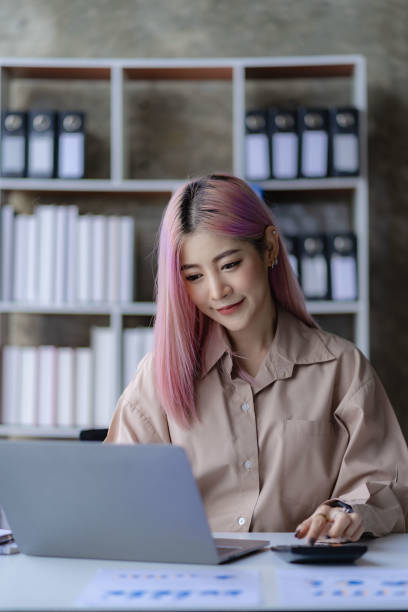 istock Young Asian accountant working in a financial office Manage sales reports using calculator with laptop and financial documents. 1484259384