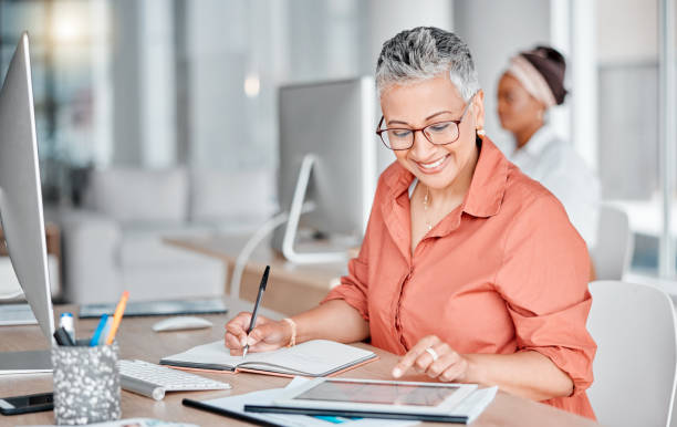 istock Book, tablet and business woman writing, research or internet browsing in office workplace. Technology, notebook and senior female employee with touchscreen for taking notes and planning strategy. 1484260211