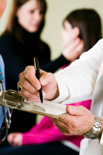 Doctor's Office Doctor showing paperwork to a nurse at a doctor's office. woman strangles man stock pictures, royalty-free photos & images