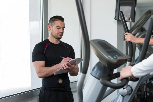 istock Trainer With Clipboard Monitors People While They Running 1484264953