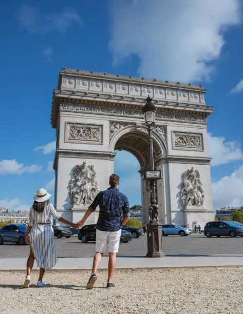 Couple on a citytrip in Paris visiting Avenue des Champs Elysees Paris France Arc De Triomphe. Men and women visiting Arc de Triomphe in Paris during summer