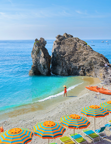 Asian women visit a Pebble beach of Monterosso Cinque Terre Italy, Chairs and umbrellas on the beach al Mare Spiaggia di Fegina beach, Monterosso, part of the Cinque Terre Italy Europe