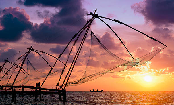 Beautiful sunset over the Chinese fishing nets in Cochin  Sunset over Chinese Fishing nets and boat in Cochin (Kochi), Kerala, India. kochi india stock pictures, royalty-free photos & images