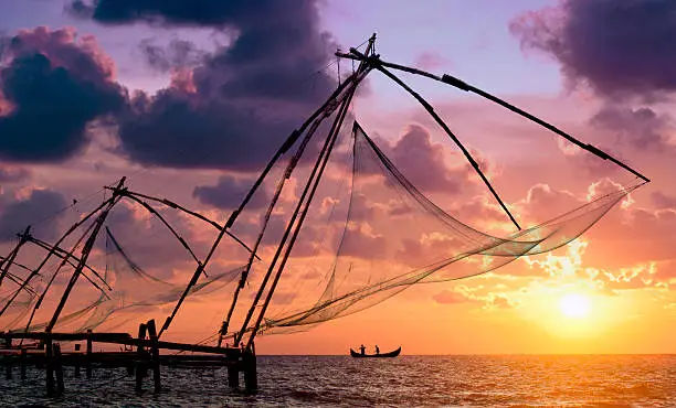 Sunset over Chinese Fishing nets and boat in Cochin (Kochi), Kerala, India.