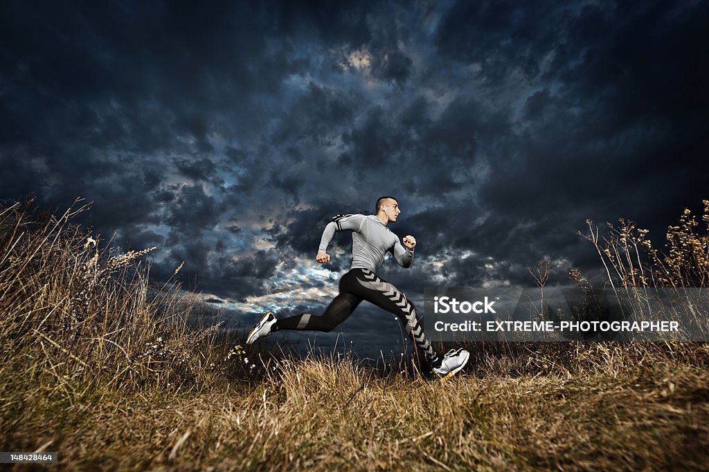 Outdoor runner Young man running across the field at sunset. Active Lifestyle Stock Photo