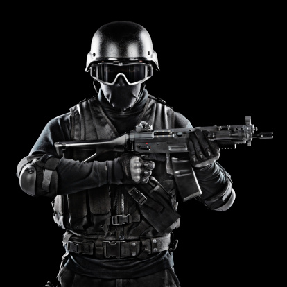 Modern military soldier holding a rifle. Studio shot on black background.