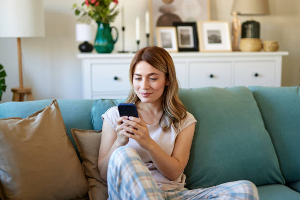 istock Happy woman text messaging on mobile phone while relaxing at home 1484288455
