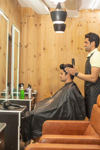 Young man having his hair styled by a barber at hair salon