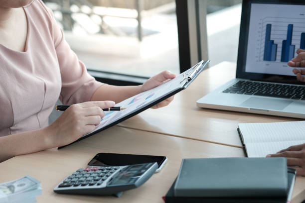 istock Businesswoman analyzing investment charts and pressing calculator buttons over documents. Accounting Concept. 1484295430