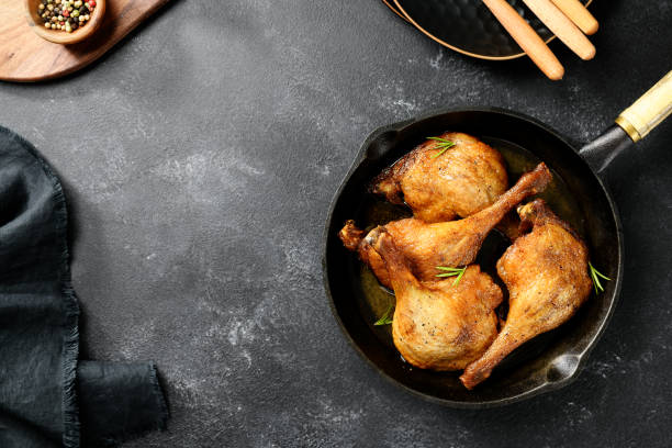 roasted duck legs confit Freshly roasted duck legs confit in pan, top view, black background confit stock pictures, royalty-free photos & images