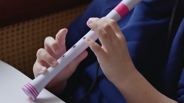 Hands of a child playing a flute close-up, fingers pinching the muzzle