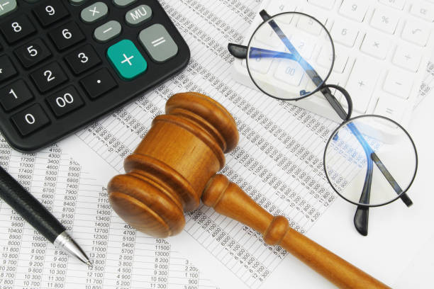 istock Glasses, calculator, pen and judge gavel on financial documents. 1484306317
