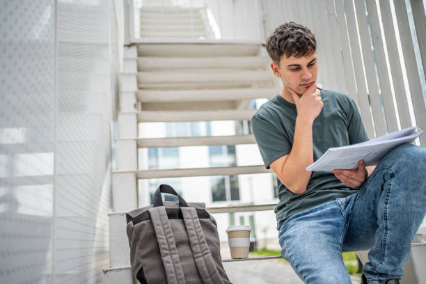 istock A high school student or student sits on the steps of his school building and studies 1484306798
