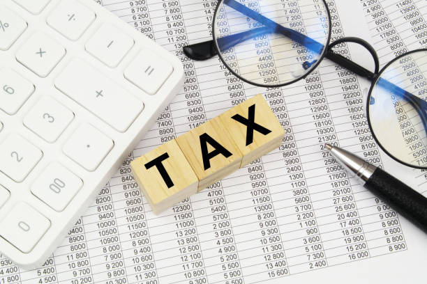 istock Word tax on cubes, calculator, pen and eyeglasses on documents. 1484307841