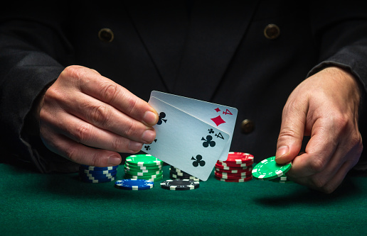 The player points to the winning combination of one pair in a poker game on a green table with chips and in a club.