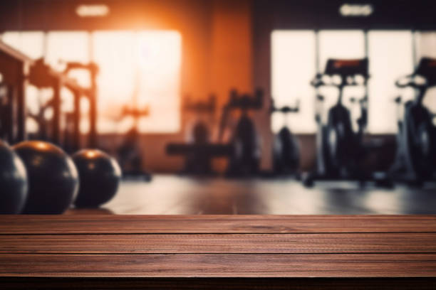 Blurred background of fitness gym and wooden table free space for product display stock photo
